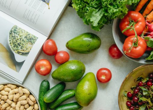 An appetizing display of fresh fruits and vegetables with a cookbook, perfect for healthy recipes.